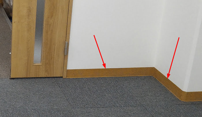 とあるオフィスのタイルカーペット床に対し貼られたソフト巾木を撮影した写真に解説用矢印を入れた写真画像②