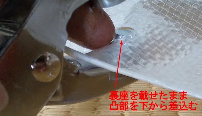 ハトメパンチの使い方とハトメの付け方解説2：裏座を凸部に載せたままシートの裏から差し込む様子を撮影した写真に解説コメントを入れた写真画像
※Original image actually taken by myself：Copyright © とある建築士の憂鬱 All Rights Reserved.